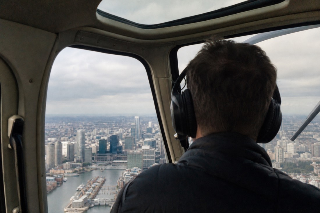 Passenger wearing a noise-canceling headset inside a sightseeing helicopter cabin